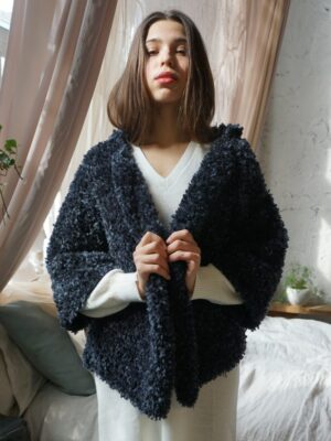 A close-up of a blue hand-knitted jacket made from boucle merino wool, available for purchase