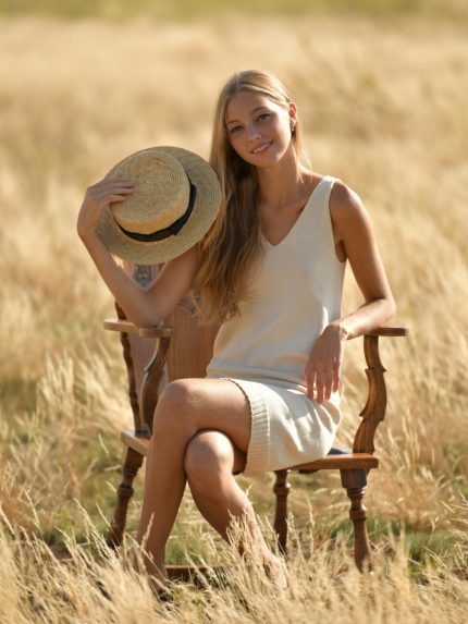 A model wearing a knitted milky basic dress from Pasma Design's dress collection, featuring a V neckline, long sleeves, and a form-fitting silhouette