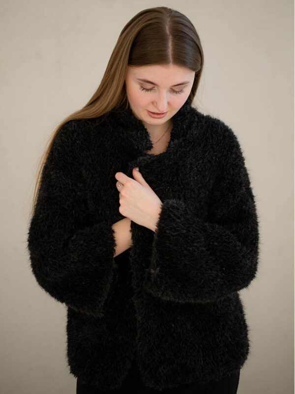 A stunning black handknitted coat made from boucle merino wool, available for purchase